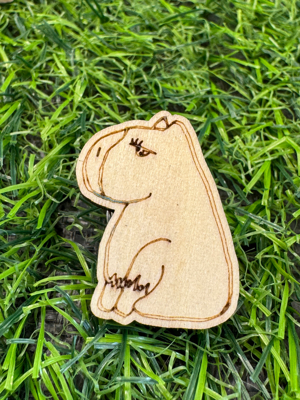 An image of a hand drawn wooden capybara pin badge